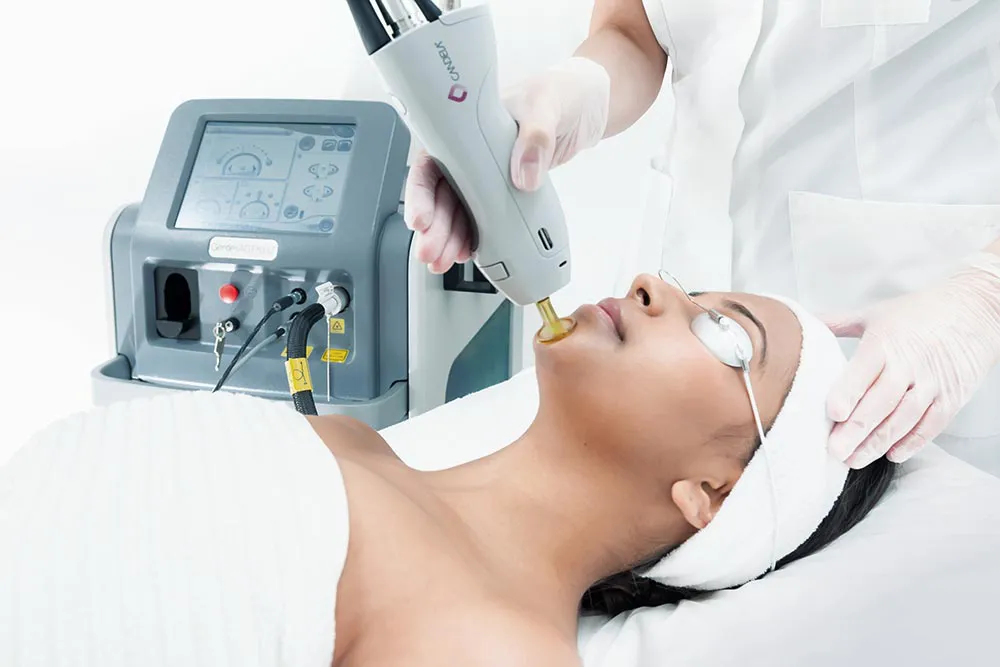 A Laser Me provider in gloves guiding the Candela GentleMax Pro handpiece across a client's skin during a laser hair reduction session